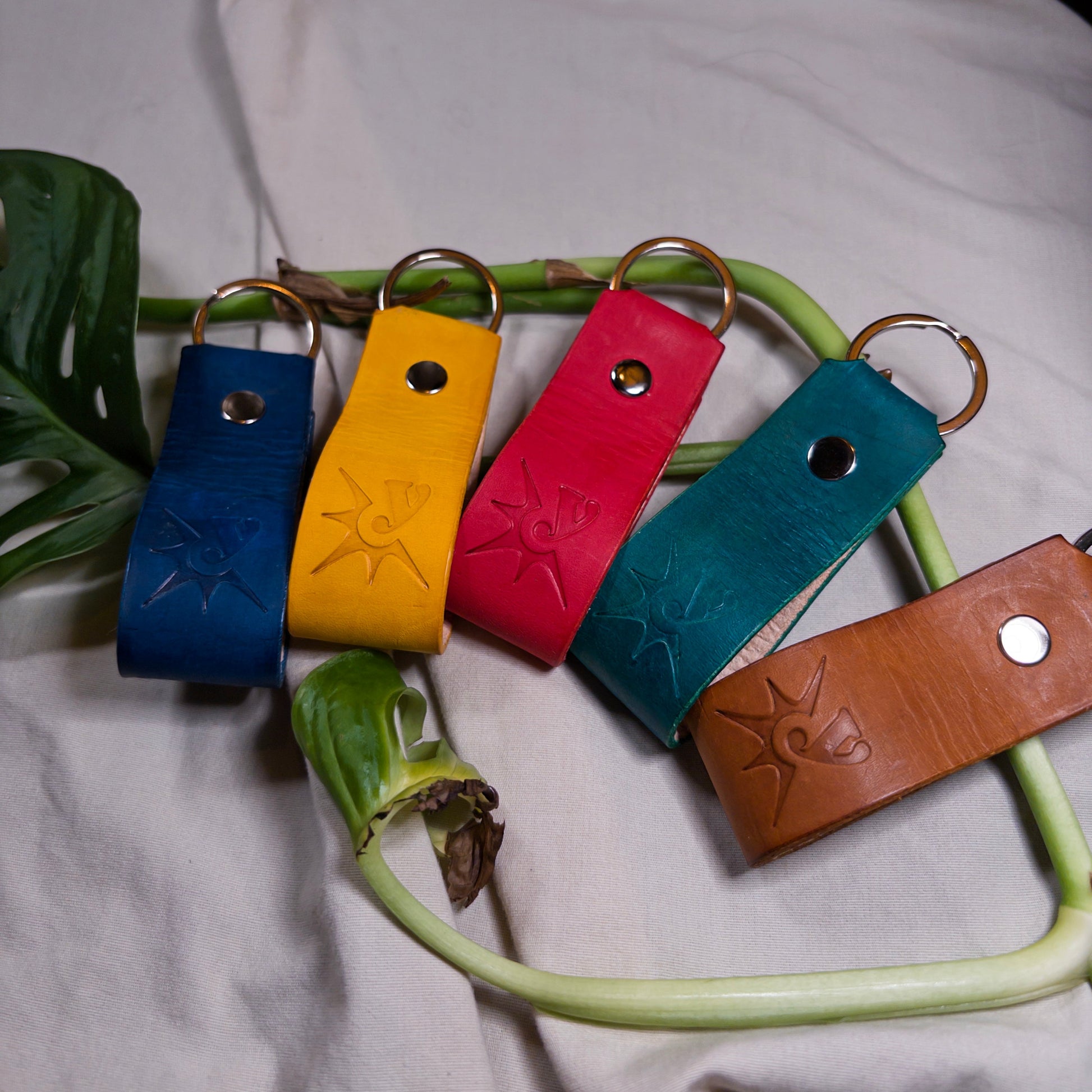 Five colorful leather keychains on a white fabric background